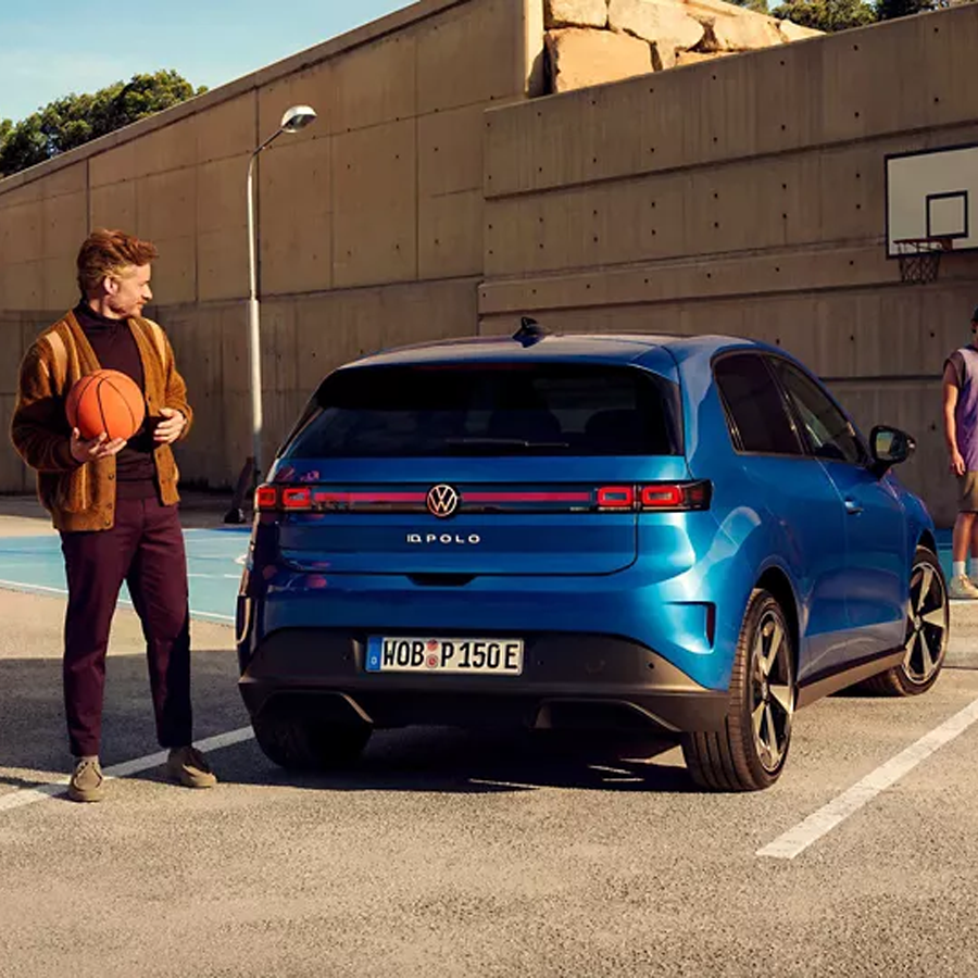VW ID.Polo von hinten, daneben steht ein Mann mit einem Basketball in der Hand